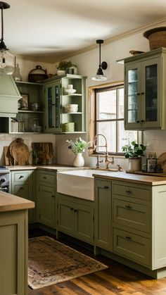 a kitchen filled with lots of green cupboards and counter top space next to a window