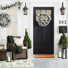 the front porch is decorated for christmas with wreaths and lanterns