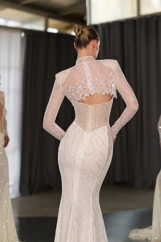 the back of a wedding dress with long sleeves and beading on it, as seen from behind