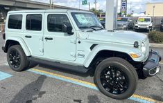 a light blue jeep parked in a parking lot next to a gas station with other cars