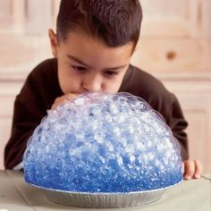 a young boy looking at a blue and white cake in the shape of a bowl