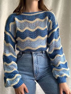 a woman is wearing a blue and white sweater with wavy knits on the sleeves