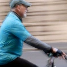 an old man riding a bike down the street in front of a blurry building