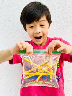 a young boy holding onto a bag filled with pencils