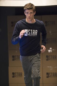 a young man is running on the street wearing a star t - shirt and jeans