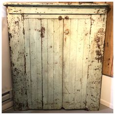 an old white wooden cabinet with peeling paint on it's doors and bottom panel