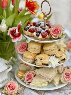 three tiered trays filled with pastries and flowers on top of a table