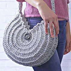 a woman holding a gray crocheted purse