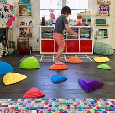 a young boy is playing with toys in the room that has many different colors and shapes on the floor