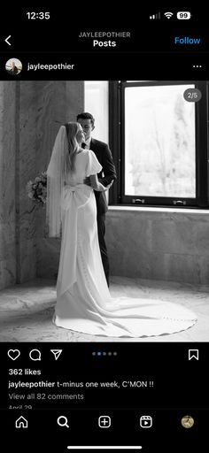 black and white photo of bride and groom kissing in front of window at their wedding