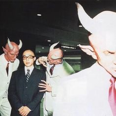 three men in suits and devil horns standing next to each other