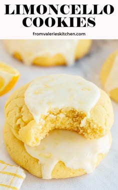 two lemon cookies with frosting on top and one in the middle, next to some sliced lemons