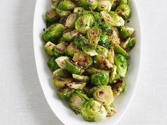 brussel sprouts in a white serving dish on a white tablecloth