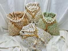 several bags with pearls and beads on them sitting on a white cloth covered bed sheet