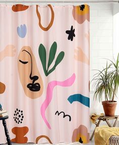 a shower curtain with an abstract design on it and a chair next to it in front of a potted plant