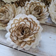 some white and gold flowers are sitting on a wooden table with wood planks in the background