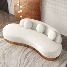 a large white couch sitting on top of a wooden floor next to a rug and mirror