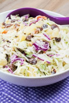 a white bowl filled with coleslaw on top of a blue and white checkered table cloth