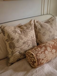 the pillows on the bed are made up with different patterns and colors, along with a rolled pillow