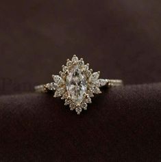 an engagement ring with a pear shaped diamond surrounded by small white and yellow diamonds on a black background