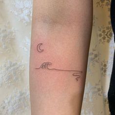 a woman's arm with a small wave and half moon tattoo on the left forearm