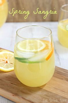 two glasses filled with lemonade and limes on top of a wooden cutting board