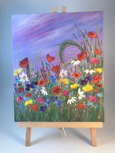 an easel with a painting on it that has colorful flowers painted on the side