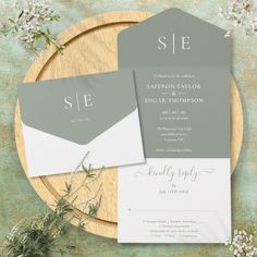 the wedding stationery is set on top of a wooden plate with flowers and greenery