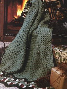 there is a green crocheted blanket on the floor next to a fire place