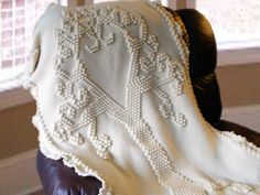 a white crocheted blanket sitting on top of a leather chair next to a window