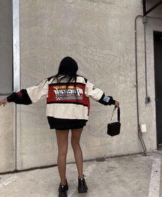 a woman standing in front of a wall with her back to the camera and arms outstretched