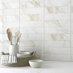 kitchen utensils in basket on counter next to white tiled wall and flooring