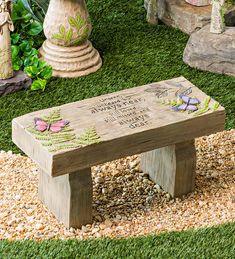 a wooden bench sitting on top of a grass covered ground next to flowers and plants