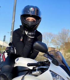 a woman sitting on top of a white motorcycle wearing a helmet and goggles