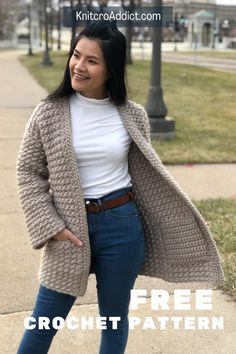 a woman standing on the sidewalk with her hands in her pockets, wearing jeans and a cardigan