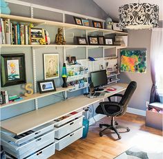 a home office with lots of storage space and artwork on the wall above it, along with two desks