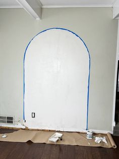 an arch is being painted on the wall in a room with hard wood flooring