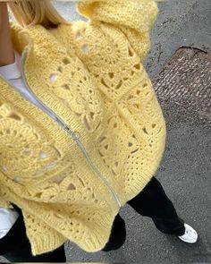 a woman wearing a yellow knitted shawl with holes in the middle and zippers down