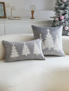 two decorative christmas trees on grey and white pillows