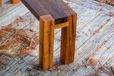 a wooden bench sitting on top of a wooden floor next to dry grass and trees