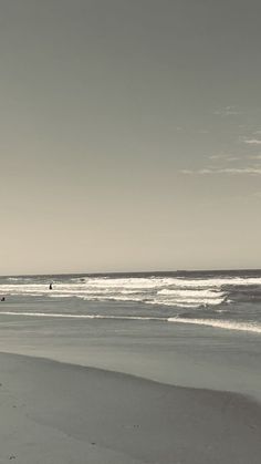 two people walking on the beach with surfboards