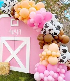 there are many balloons in the shape of farm animals on this pink house with cow print