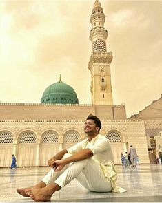 a man sitting on the ground in front of a building