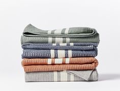 four folded towels stacked on top of each other in different colors and patterns, with one folded