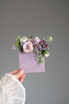 a person holding up a piece of paper with flowers on it in front of a gray wall