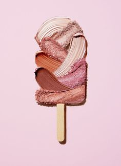 a popsicle with different shades of pink and brown on it's top, in front of a pink background