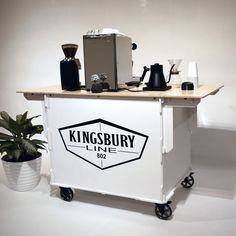 a white cart with kingsbury line logo on the side and coffee maker next to it