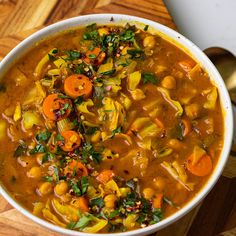 a white bowl filled with soup on top of a wooden table next to a spoon