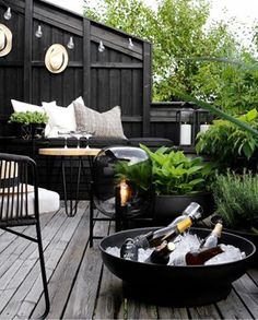 an outdoor deck with chairs, table and bottles of wine in the bowl on it