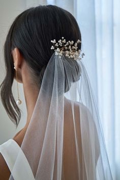 the back of a bride's head wearing a veil with flowers and pearls on it